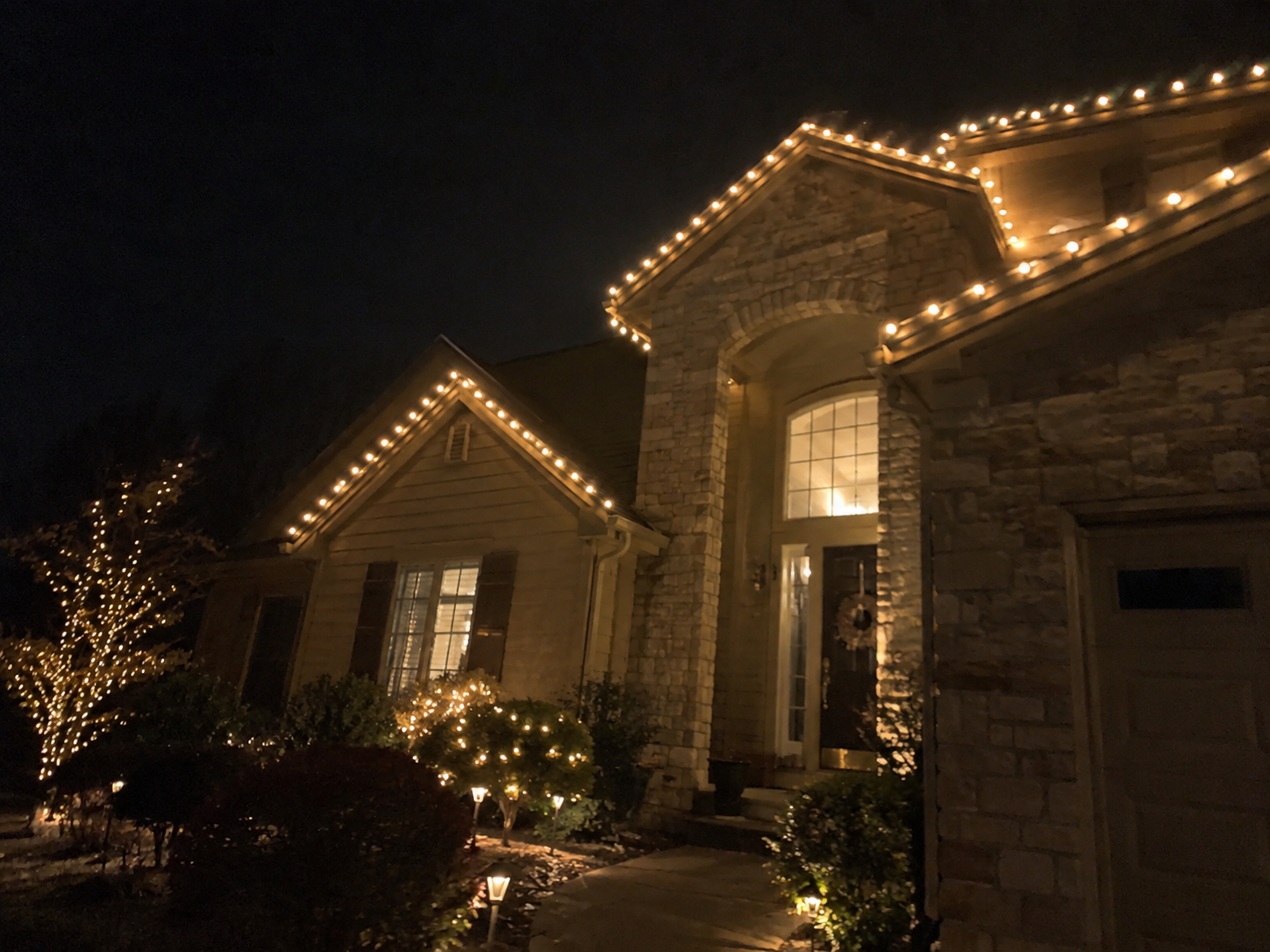 Stone entryway gables outlined in warm white holiday lights